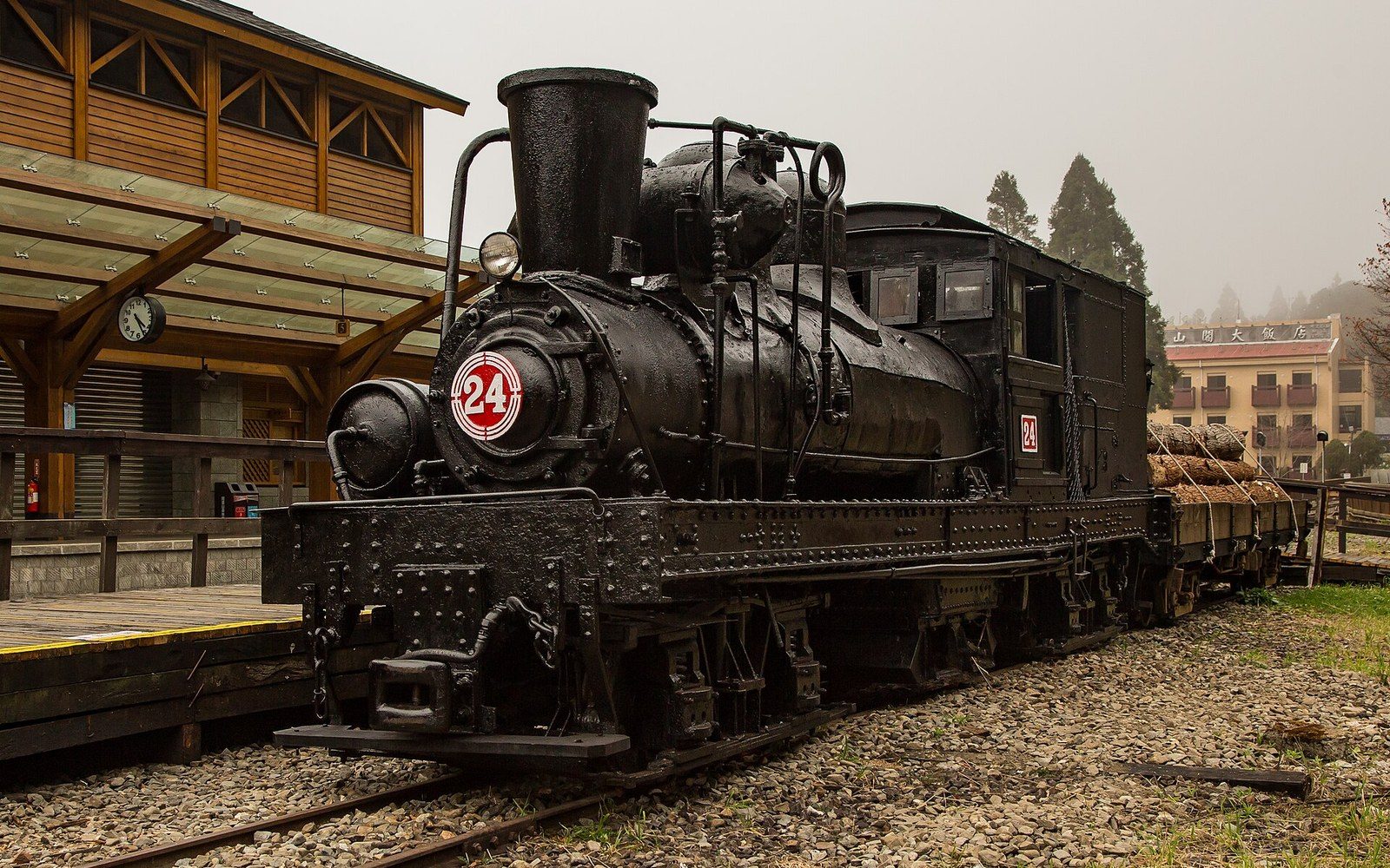 A black steam locomotive numbered 24 sits at a wooden station platform