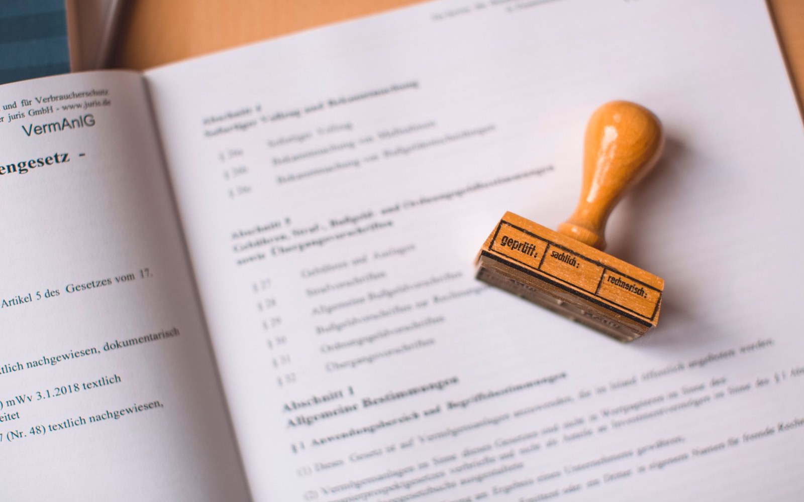 A wooden inspection stamp resting on an open German legal statute book
